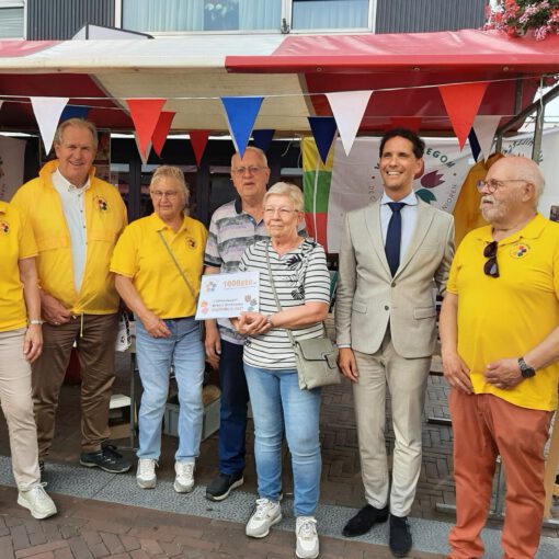 Bestuur van VVS Hillegom in hun felgele t-shirts met in het midden een senior echtpaar en de burgemeester in een cremekleurig pak.